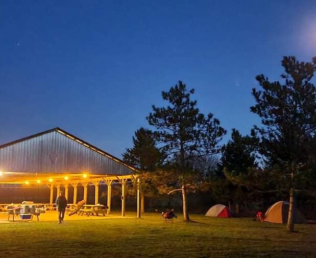 Photo of the pavillion at night, with lights from the rafters all illuminated